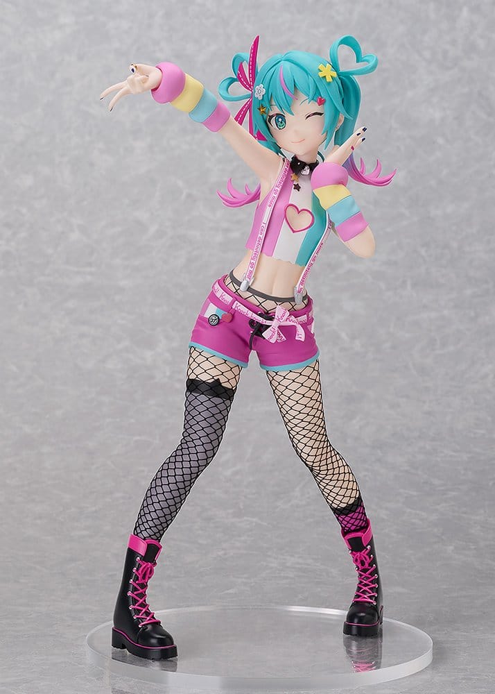 A colorful anime-style figurine of a character with bright turquoise hair, wearing a pastel pink, blue, and yellow outfit with fishnet stockings and black boots, posed on a clear round display base against a gray studio background.