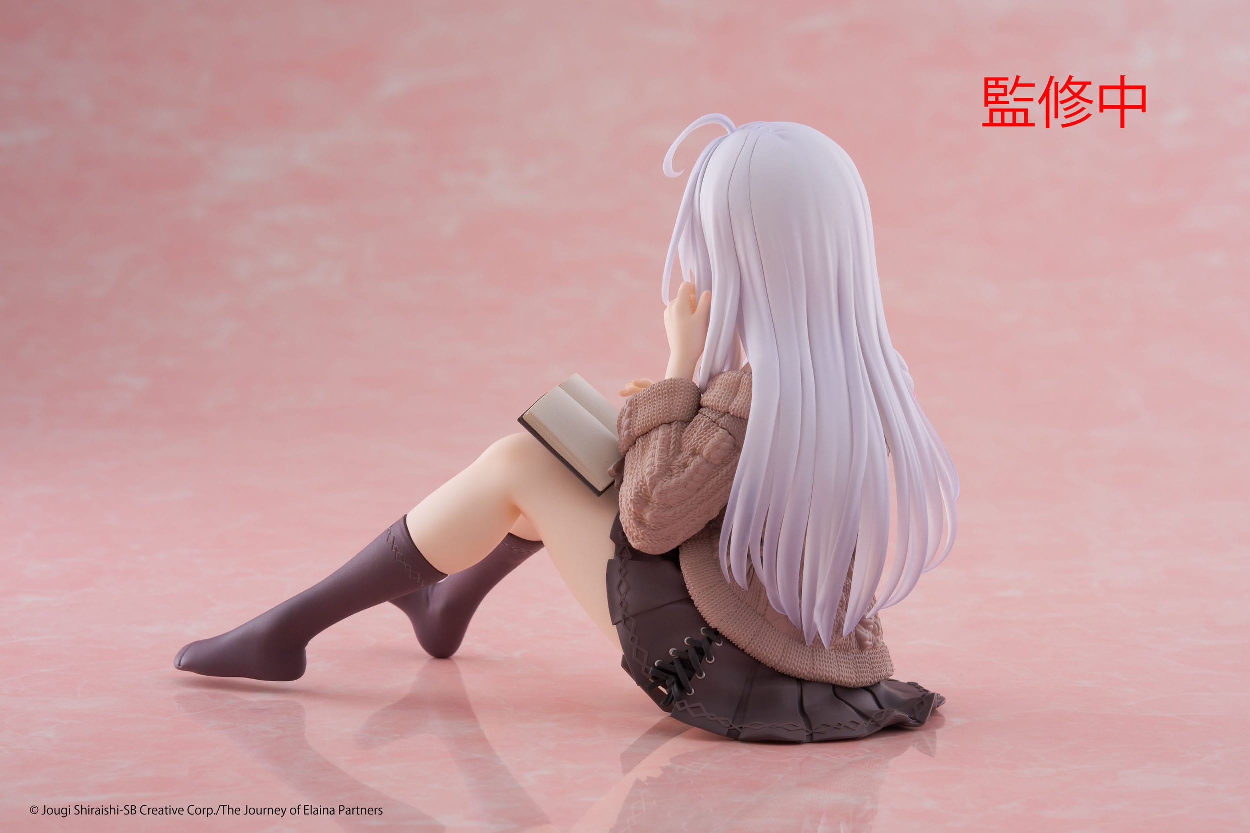 Figurine of a character with long white hair sitting on a pink background