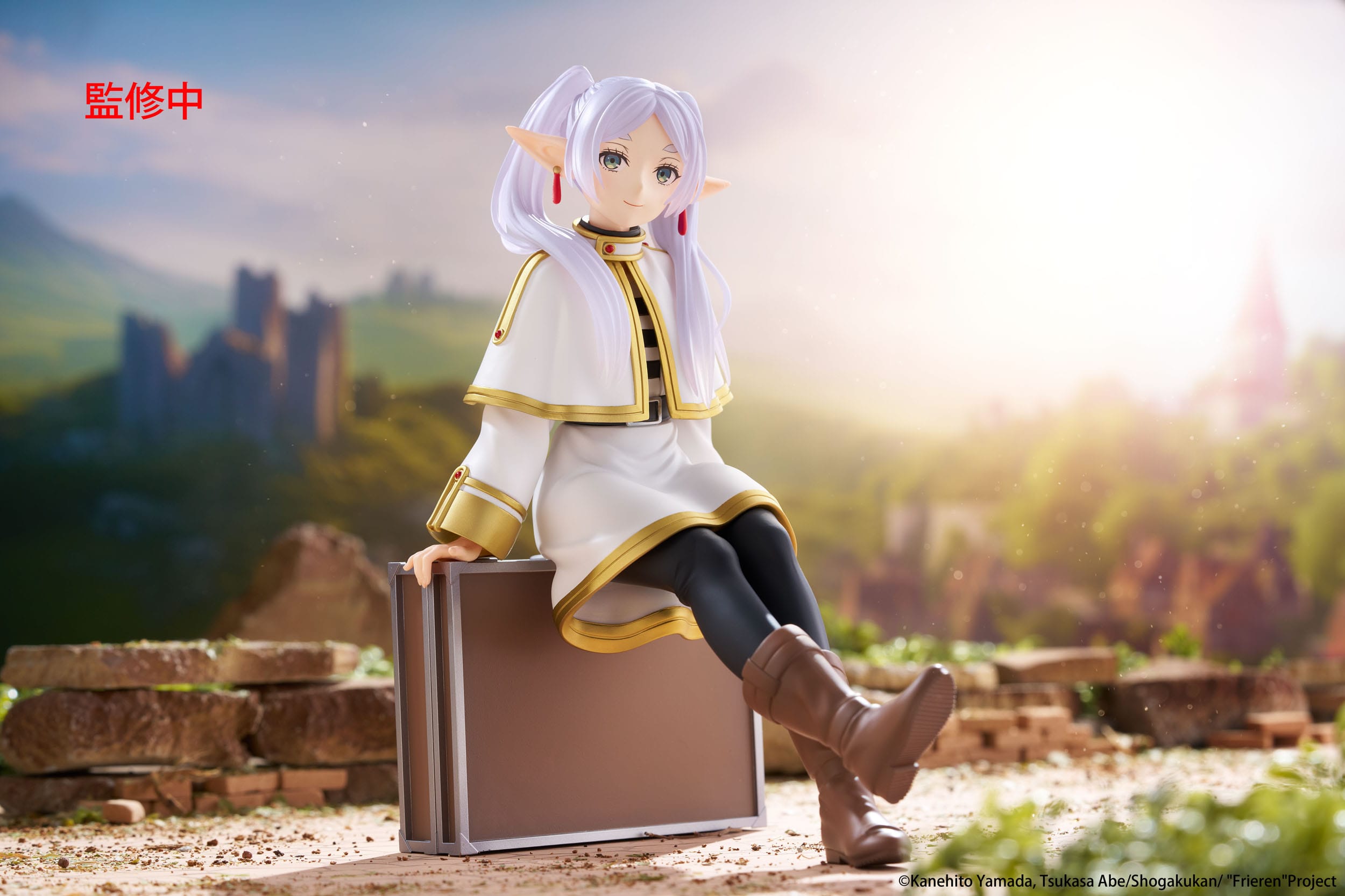 Figurine of a character with white hair and elf-like ears sitting on a suitcase against a scenic background.