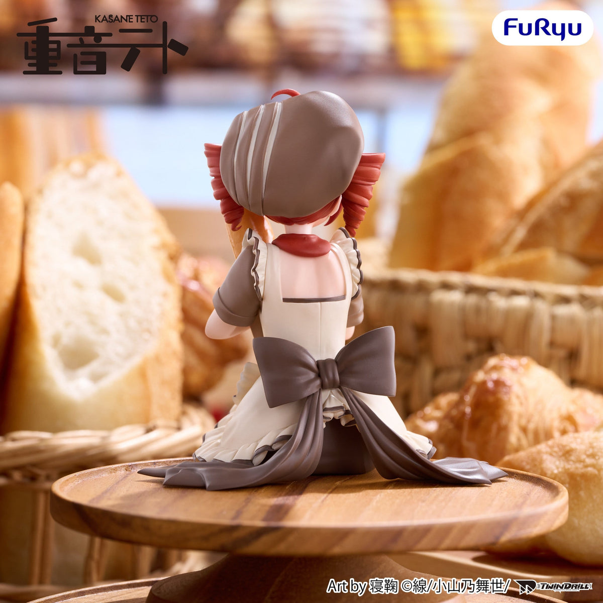 A stylized anime figurine shown from the back, seated on a wooden stand in front of a blurred bakery background with bread baskets. The character wears a white dress with a large gray bow and gray hair accessories.