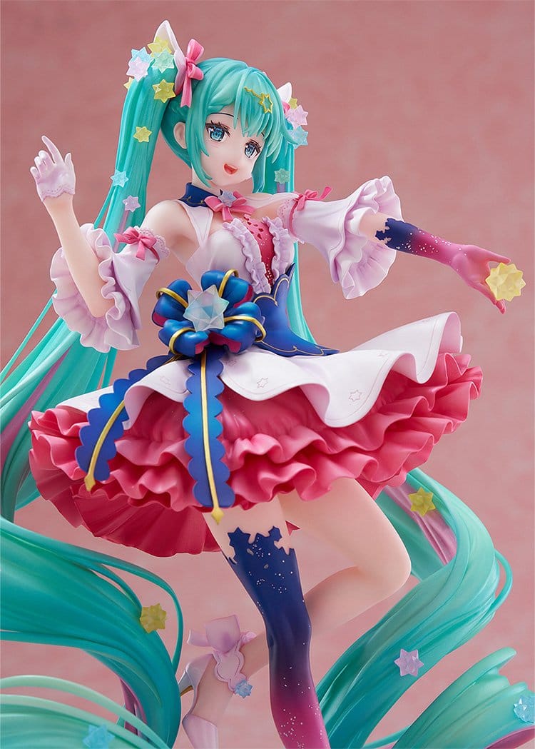 Colorful anime-style figurine with turquoise hair and a pink and blue outfit on a pink background