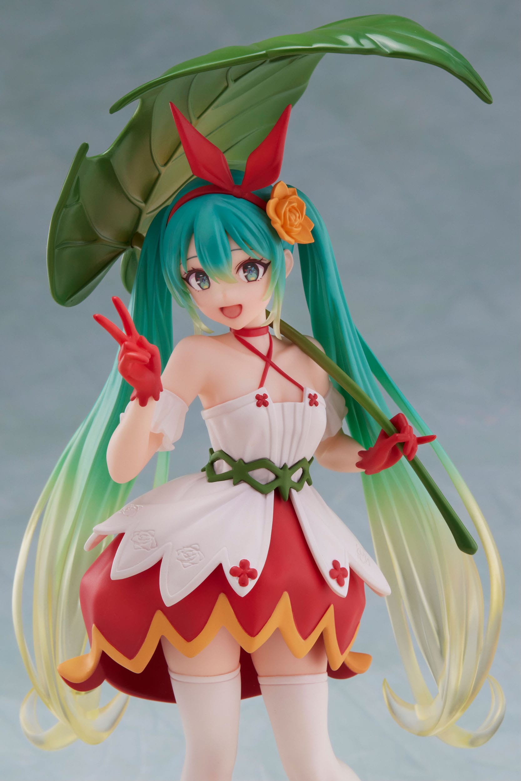 Anime character figurine with green hair and a red and white outfit on a gray background