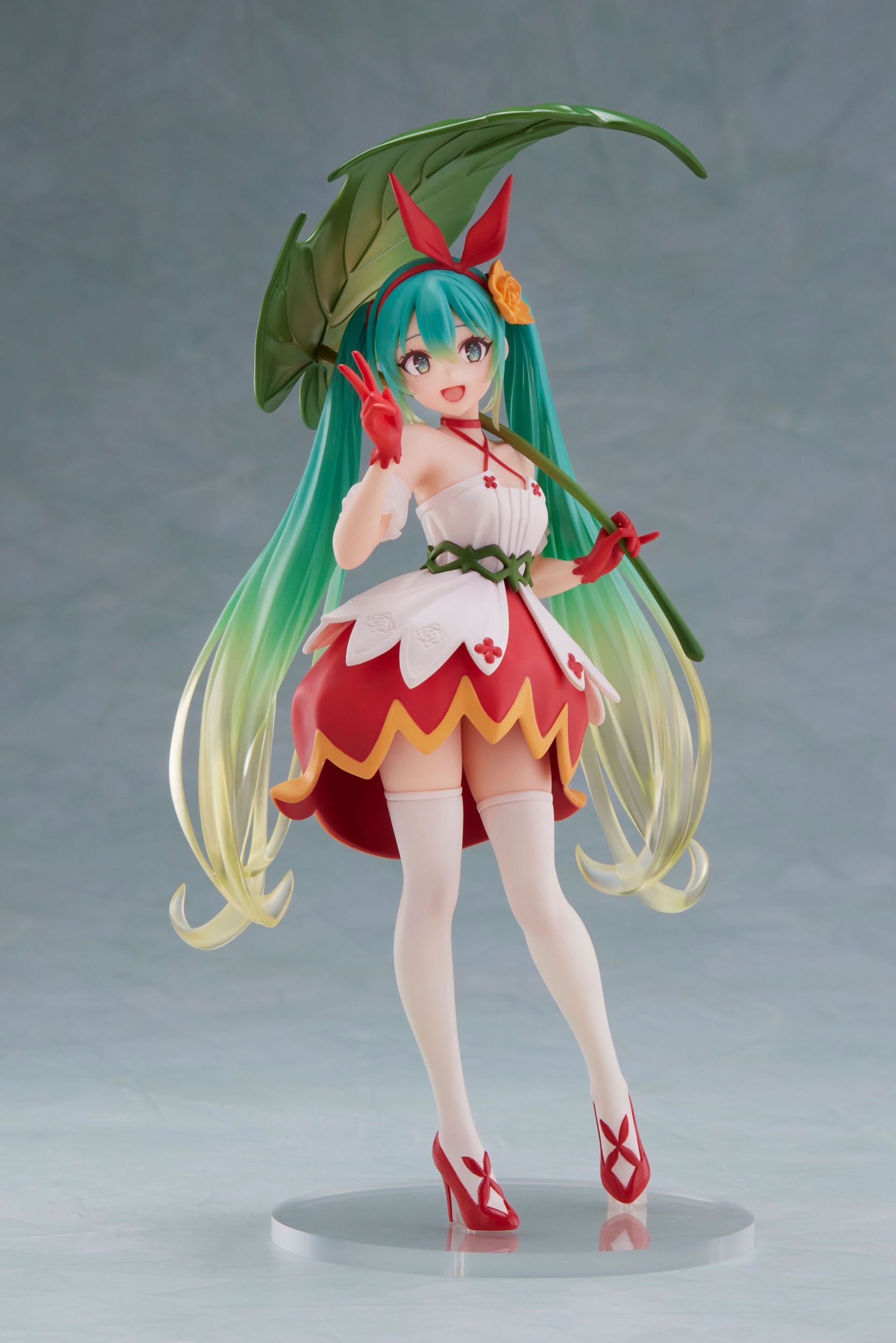 Anime character figurine with green hair and red outfit on a gray background