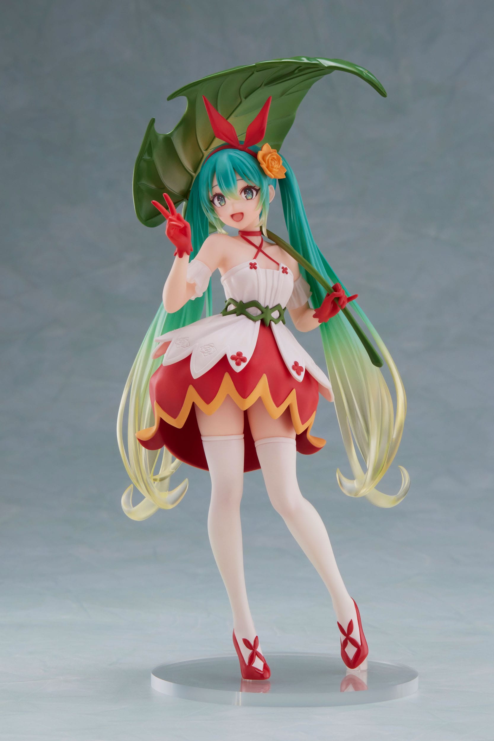 Anime character figurine with green hair and red outfit on a gray background