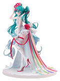 An anime figurine of Hatsune Miku in a white wedding dress with a long multicolor ribbon train, turquoise hair, and a pink crown, standing on a white base against a white background.