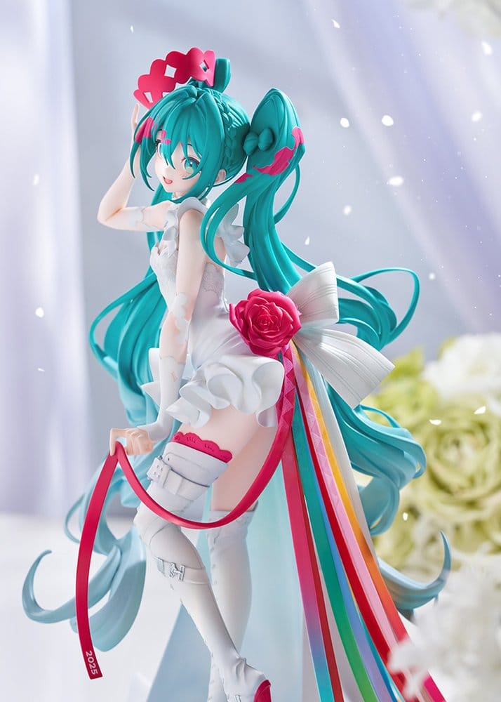A detailed anime figurine of Hatsune Miku in a white and pink outfit with long teal hair, pink bows, and colorful ribbons, posed against a soft, blurred light background with white flowers.